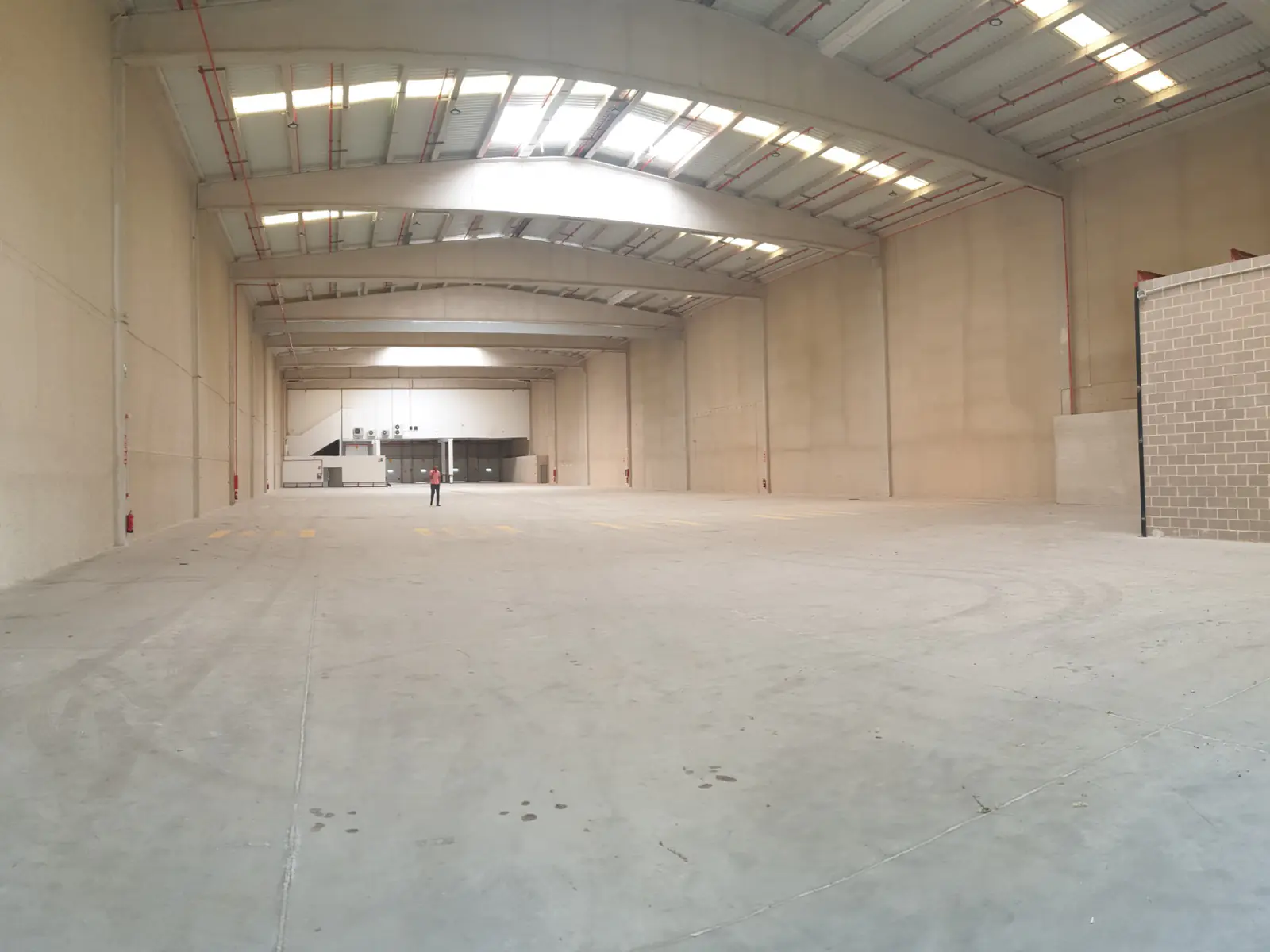 Interior de nave logística con estructura metálica y lucernarios en cubierta