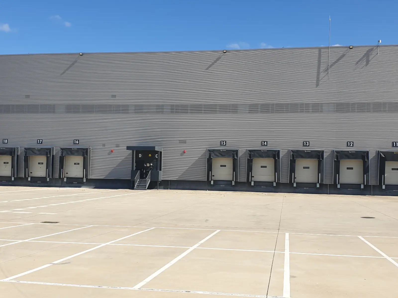 Fachada de nave logística con muelles de carga y zona exterior de maniobra