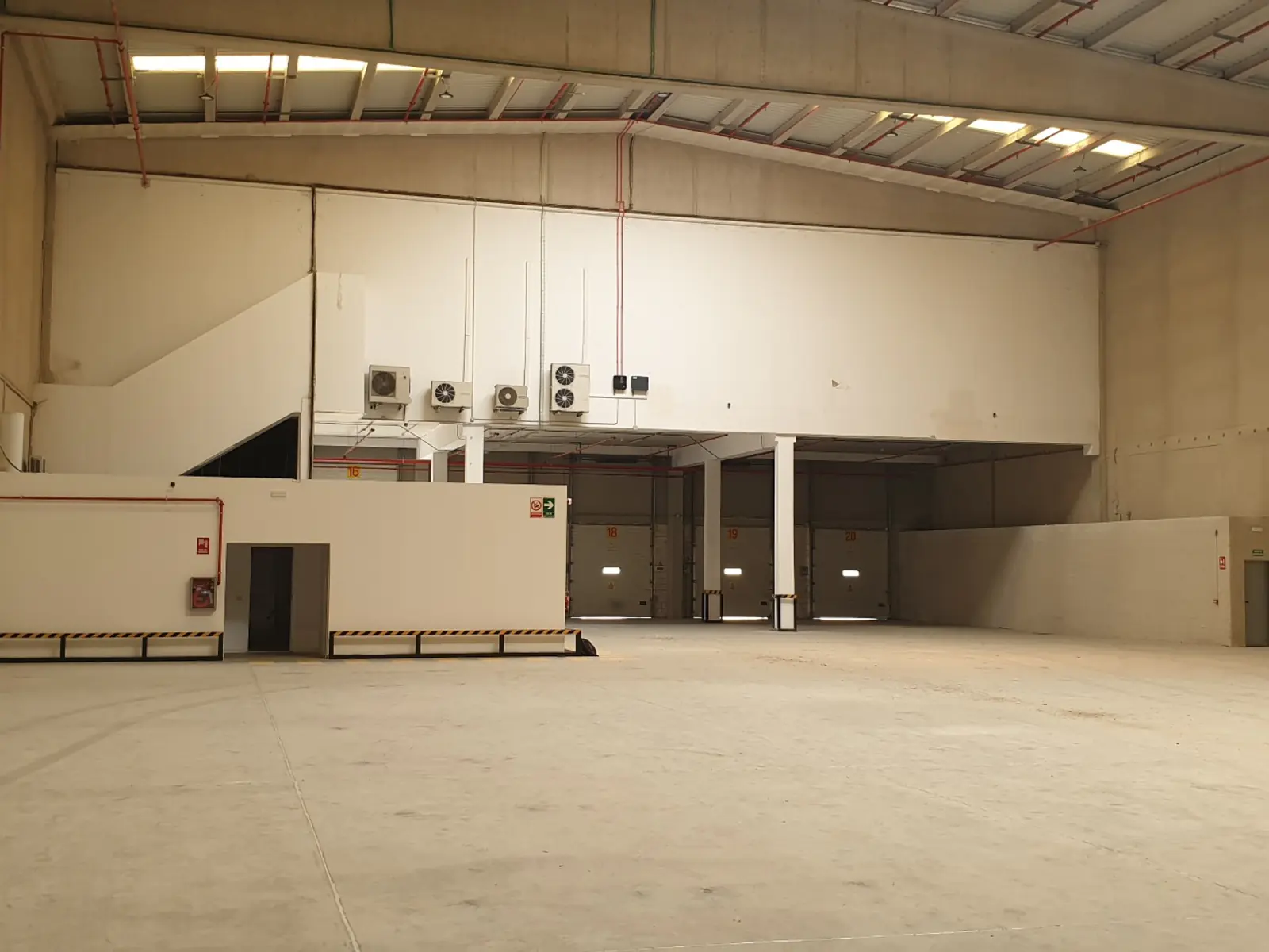 Interior de nave logística con muelles de carga y módulos de oficina