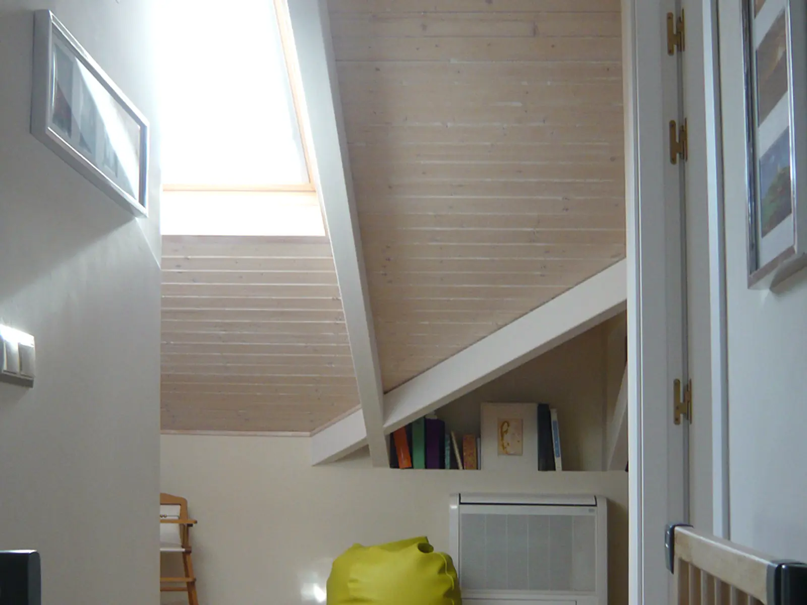 Espacio acondicionado bajo la cubierta inclinada de la vivienda, con iluminación natural a través de una ventana de tejado