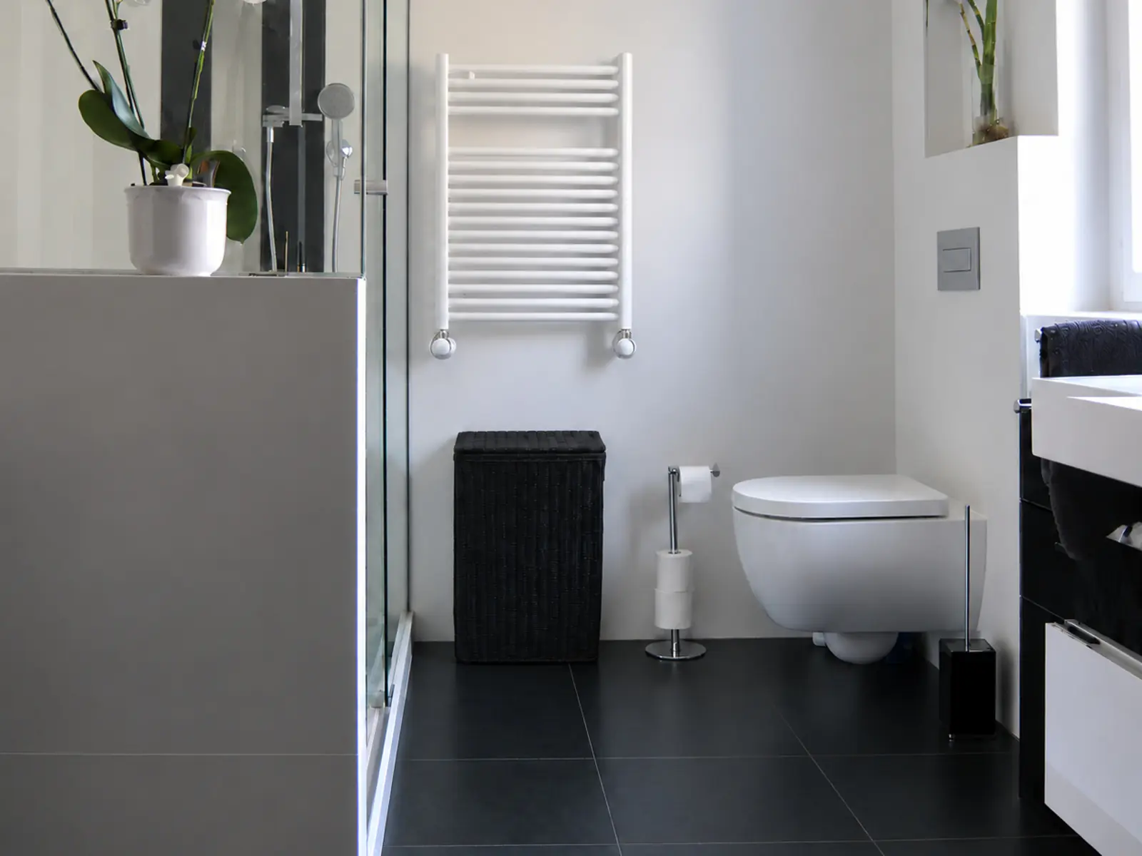 Baño de la misma vivienda unifamiliar rehabilitada, con ducha acristalada y sanitarios suspendidos