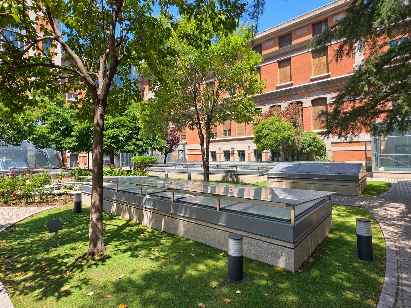 Patio histórico del Hospital Universitario Santa Cristina, con jardín, lucernarios y fachadas de ladrillo y piedra